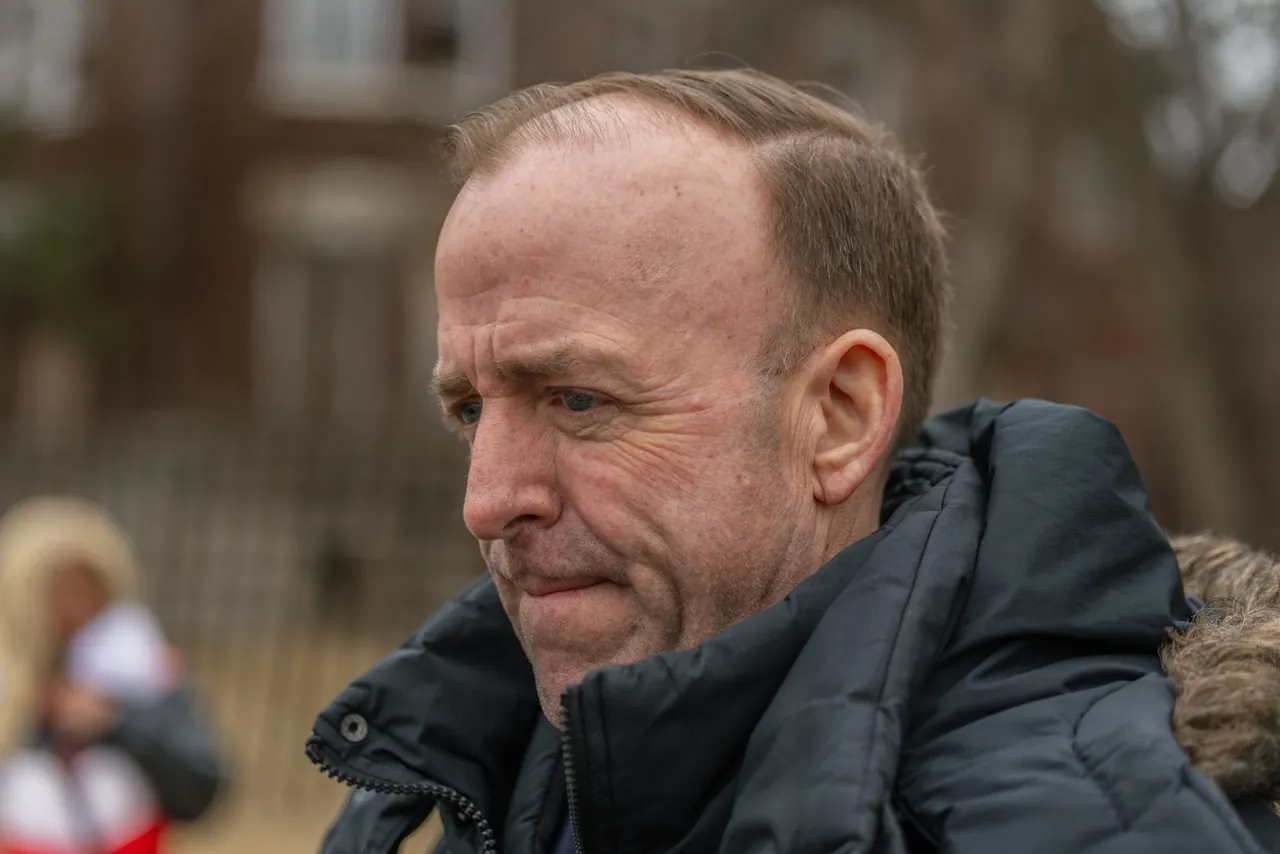 A man in a winter coat, eyes down