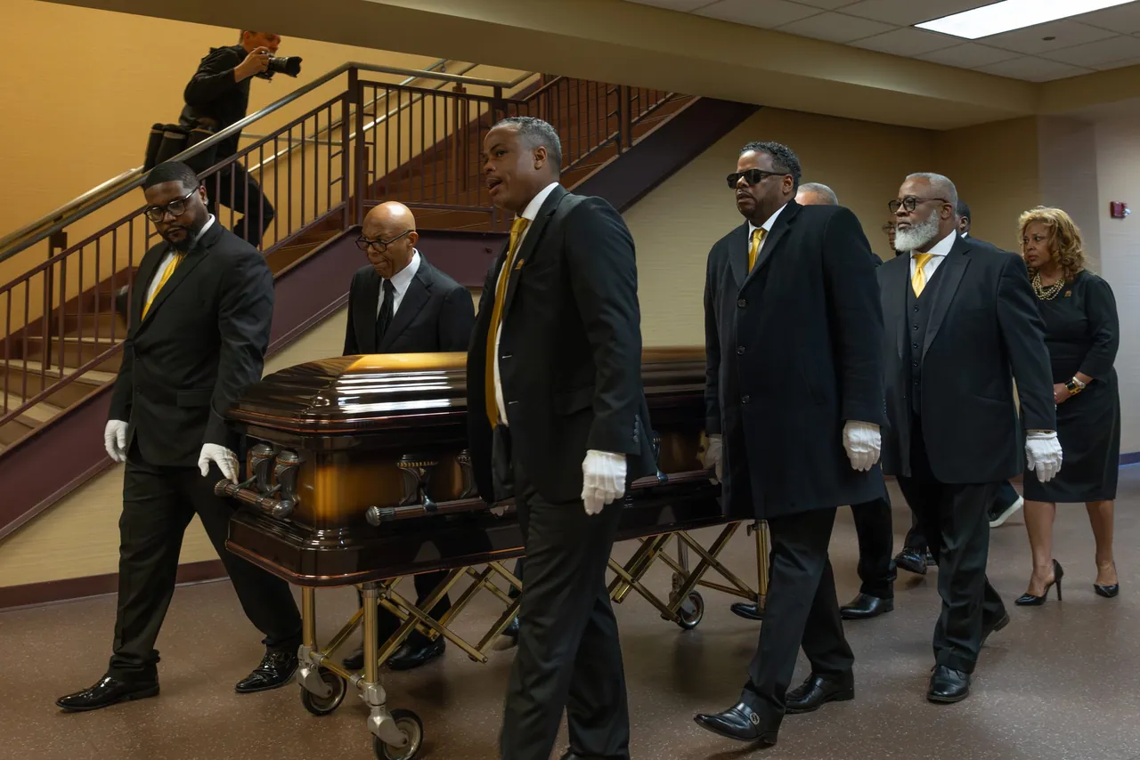 Pallbearers in white gloves carry the casket past a staircase