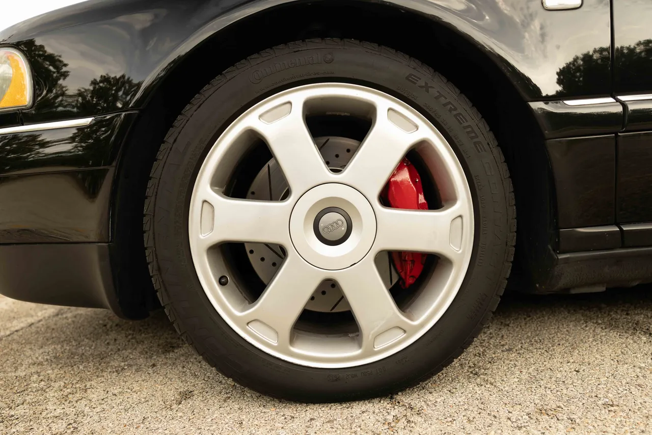 A silver wheel with a red brake caliper