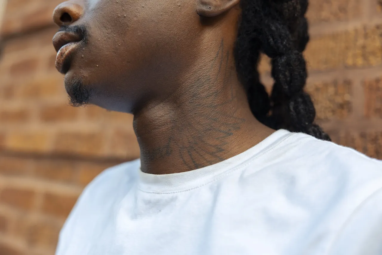 Close crop of a jaw and a white T-shirt against brick