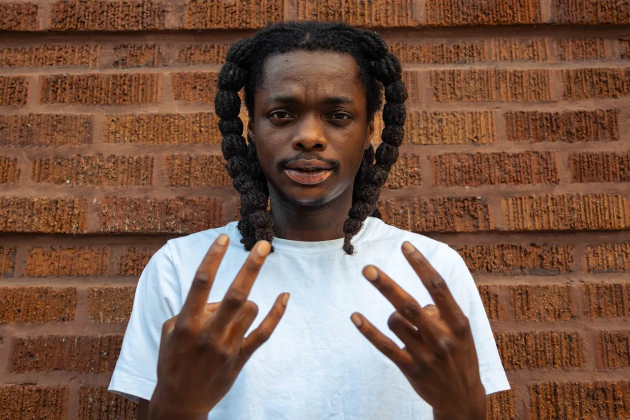 A young man with braids gestures with both hands
