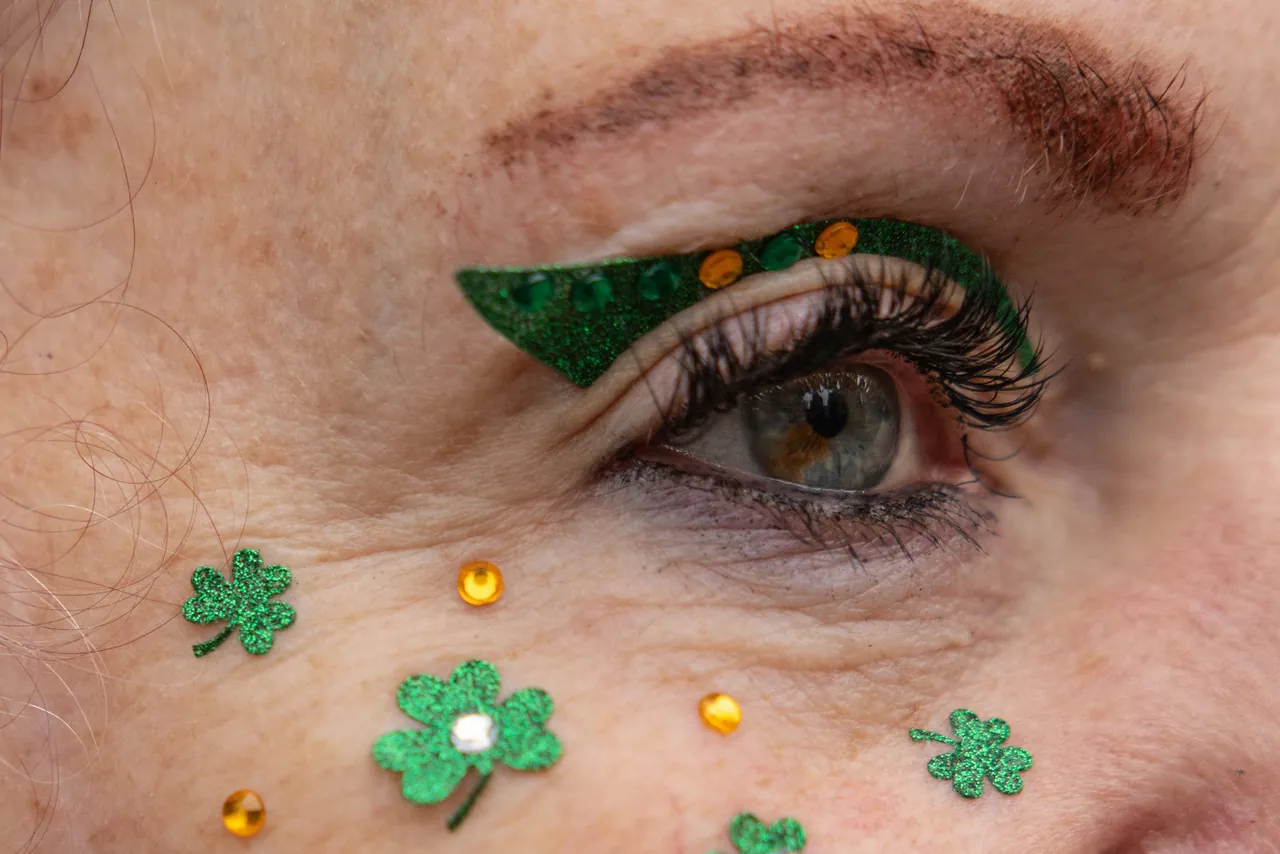 Close-up of an eye painted with green glitter and shamrocks