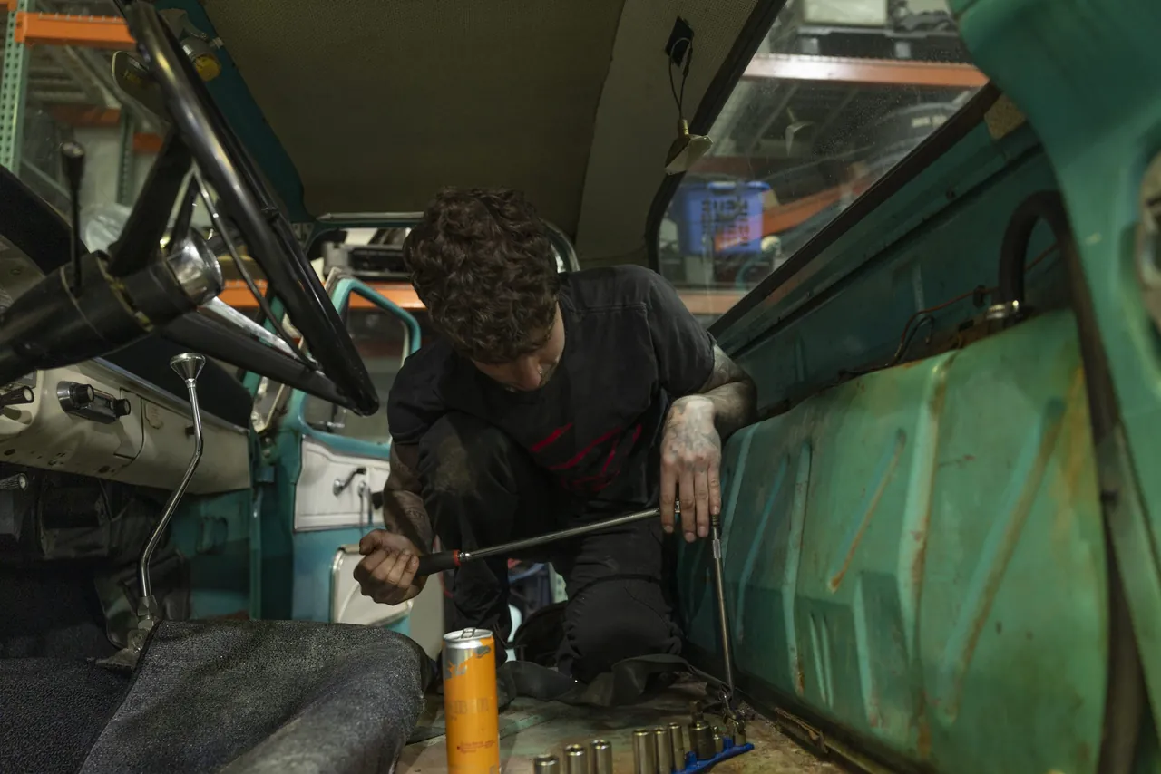 A mechanic seen through the open frame of a car