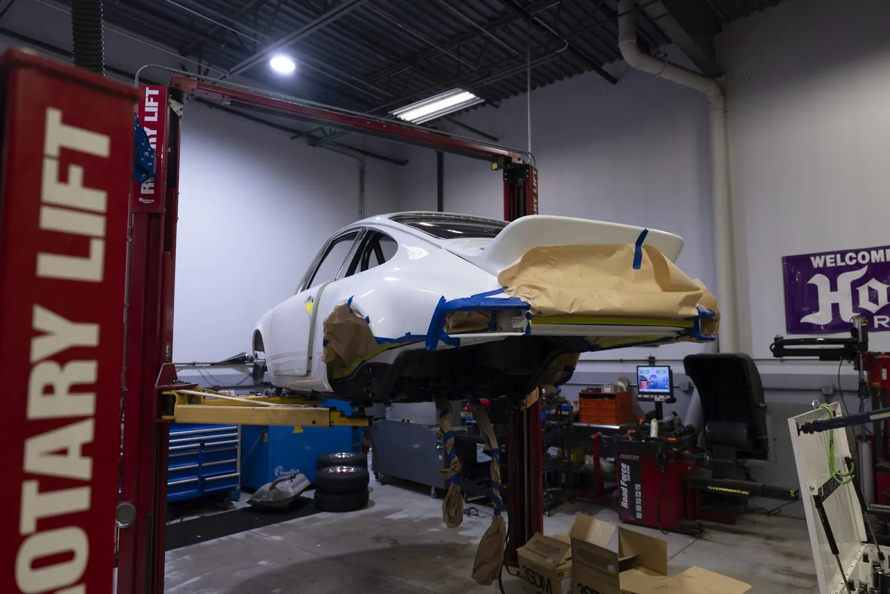 A classic Porsche raised on a lift across the shop