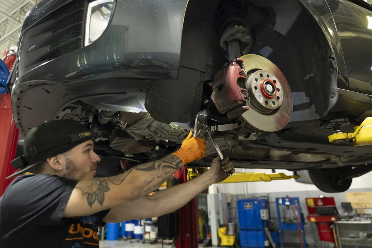 A mechanic crouches at a brake assembly