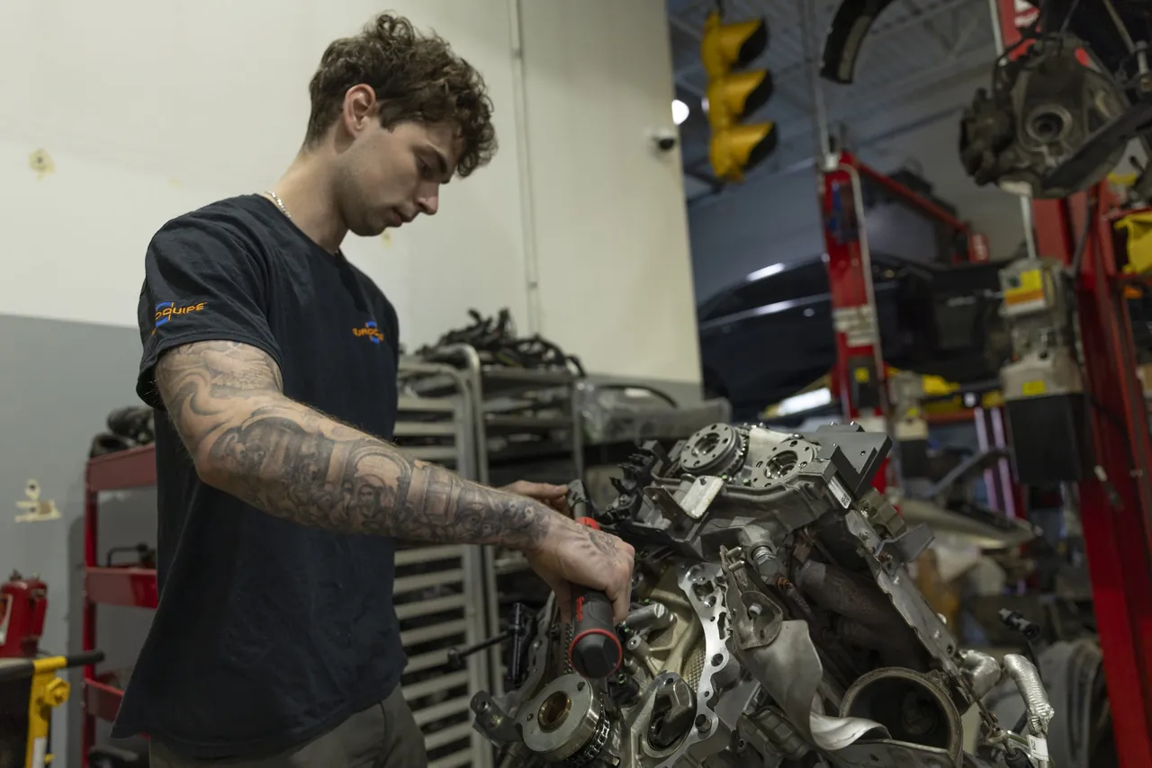 A mechanic works on an engine pulled from the car