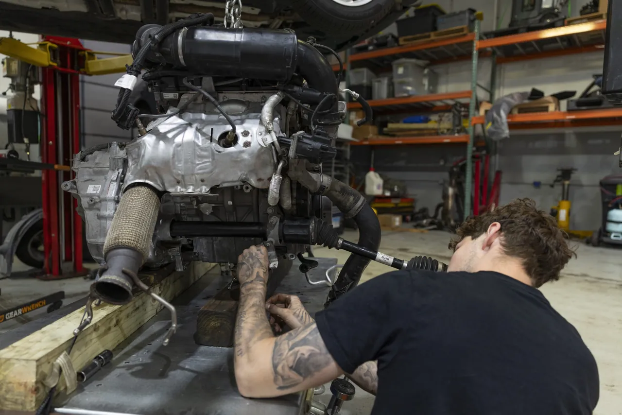 A mechanic leans into an engine on a stand