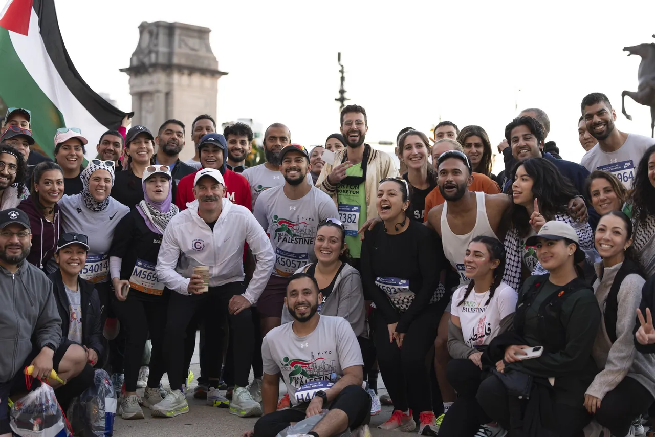 A running group poses for a photo under a flag