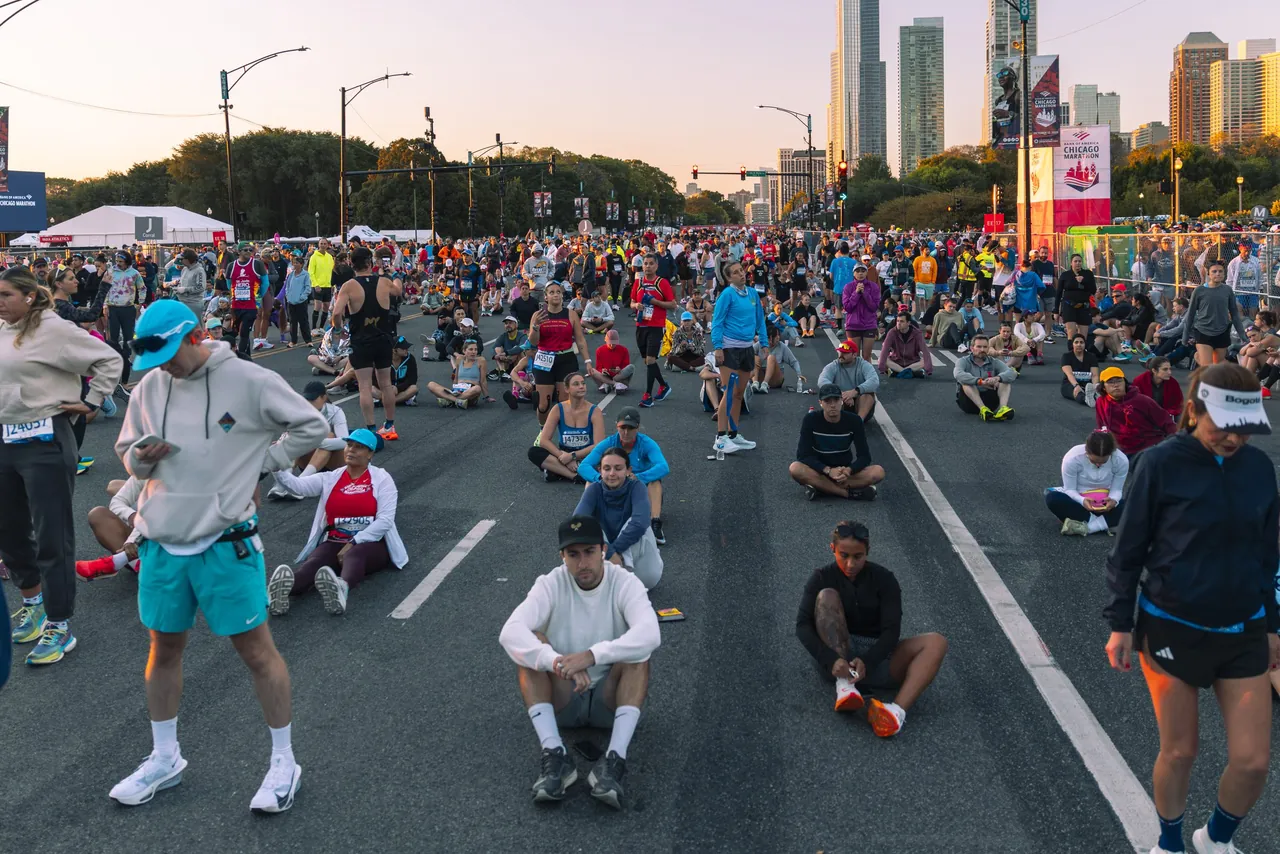 Runners stretch and sit on the street before the marathon start