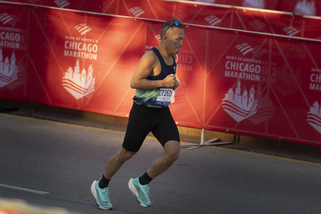 A marathon runner passes a red Chicago Marathon banner