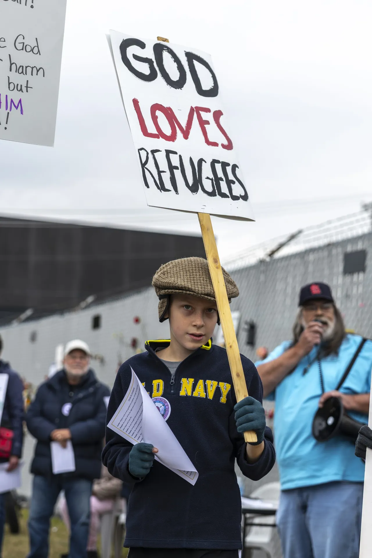 A man holds a sign reading God loves refugees