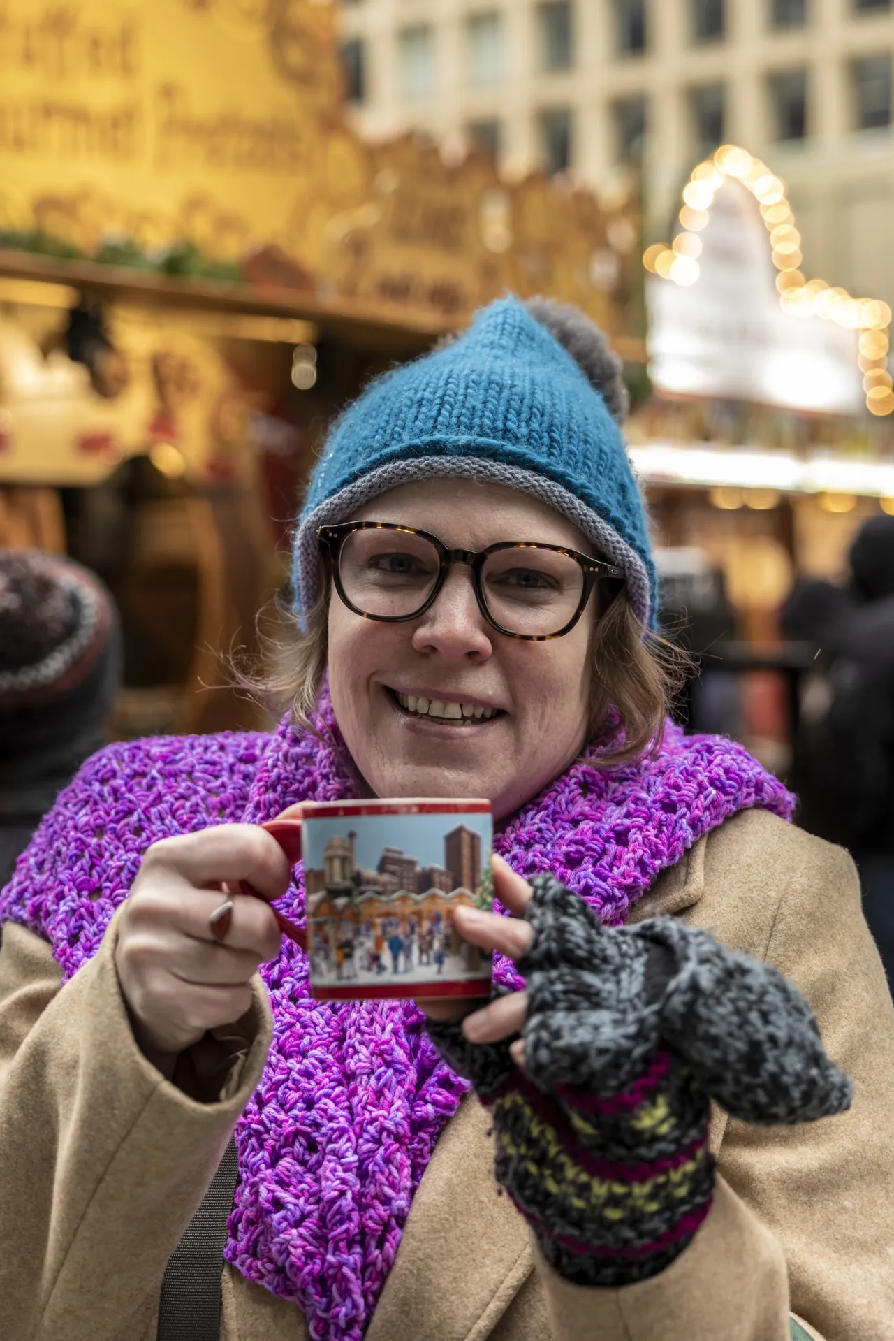 A woman in a blue hat holds up a souvenir mug