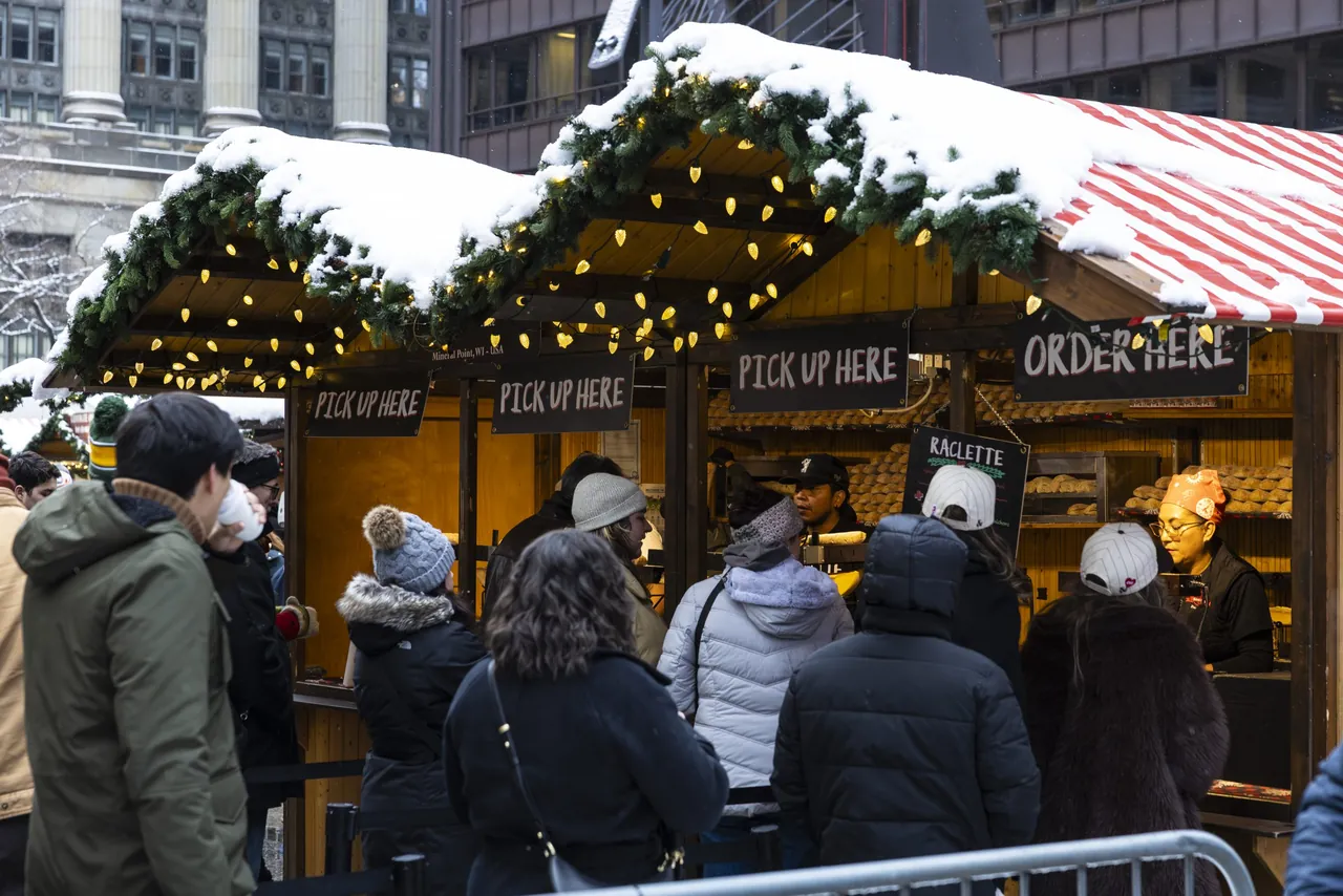 Shoppers line up at snow-covered market huts