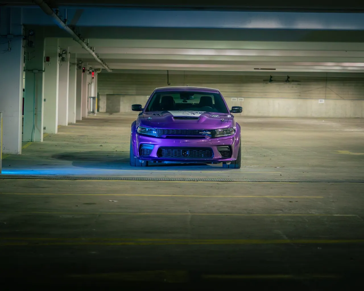 A purple muscle car alone in a parking garage